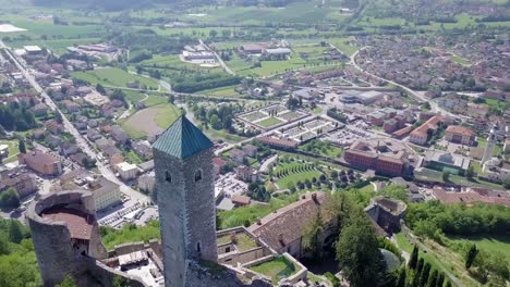 Aerial-view-of-the-Tower-of-Castel-Telvana-with-drone-flying-around-the-tower-and-tilting-up-to-reveal-an-amazing-view-of-Borgo-Valsugana-in-Trentino,-Italy