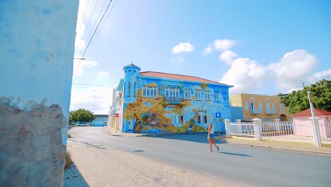 Girl-walking-past-painted-house-in-Scharloo-neighborhood,-Willemstad,-Curacao