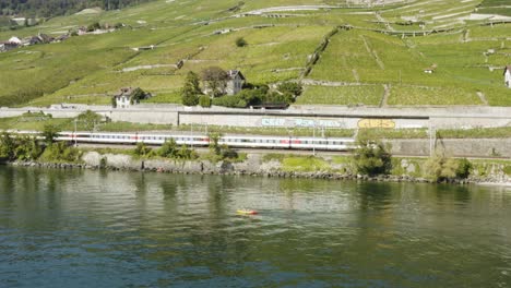 Luftumlaufbahn-Um-Kajak-Auf-Dem-Lake-Leman-Mit-Schweizer-Zug,-Der-Am-Ufer-Entlang-Fährt