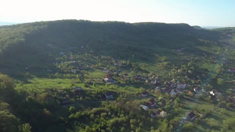 Aerial-view-of-village-brightly-lit-by-morning-sun,-rural-habitat,-countryside-panoramic-shot
