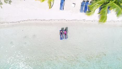 AERIAL:-Girls-lounging-on-caribbean-beach-resort
