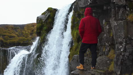 Hinter-Einem-Mann,-Der-Den-Wasserfall-In-Roter-Jacke-In-Zeitlupe-Beobachtet