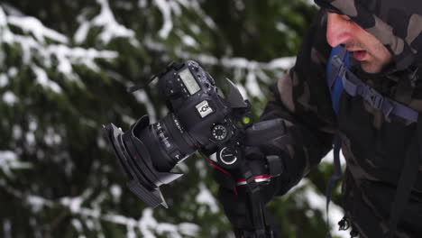Photographer-in-snowy-forest,-close-up-while-taking-photos