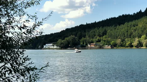 Pancharevo-lake-during-a-sunny-day,-with-a-sailboat-moving-on-the-lake