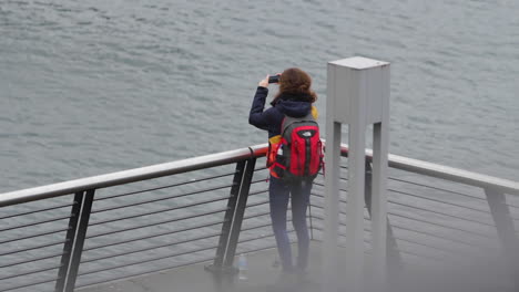 Tourist-taking-photos-on-a-bridge-near-a-lake