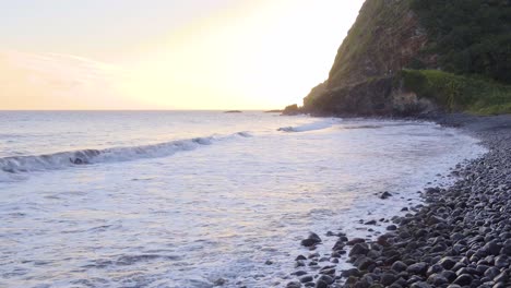Low-line-view-of-the-waves-breaking-on-a-rocky-shore-on-Hawaiian-island,-Maui-during-sunset