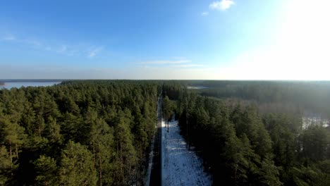 An-aerial-view-of-a-road-going-through-the-forest-during-winter-season,-Poland