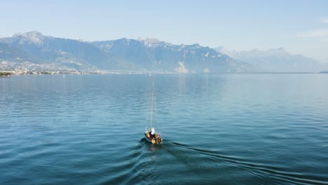 Aerial-orbit-around-small-sailboat-on-lake-Léman-in-front-of-Saint-Saphorin,-Lavaux---Switzerland-The-Alps-in-the-background