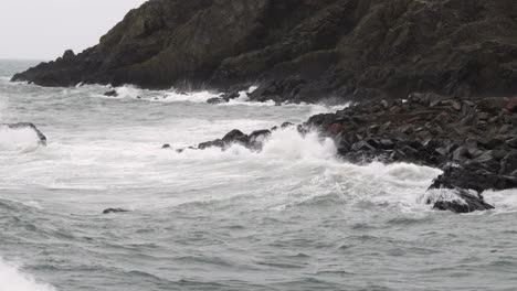Rough-Autumn-tide-crashes-in-on-dark-rocks-in-the-small-village-of-Port-Patrick,-Dumfries-and-Galloway,-Scotland