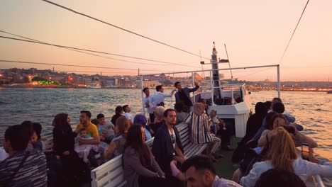 Cámara-Lenta:-Personas-No-Identificadas-Tienen-Un-Recorrido-En-Barco-Por-Estambul-Con-Vista-Al-Bósforo-Y-La-Nueva-Mezquita-Al-Atardecer-En-Estambul,-Turquía