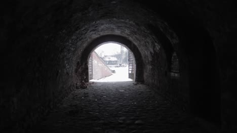 Caminando-Lentamente-En-Un-Túnel-Negro-Oscuro-Hacia-La-Entrada-Brillando-En-La-Distancia