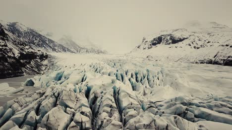 Gletscherzunge-In-Island,-Gefilmt-Von-Einer-Drohne-Mit-Verschiedenen-Filmischen-Bewegungen,-Die-Ein-Wolkiges,-Dramatisches-Konzept-Bei-Winterlichen-Bedingungen-Zeigen