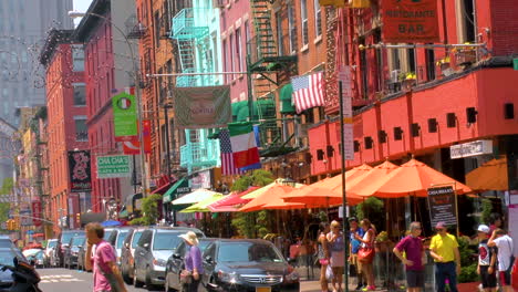 Street-scene-in-Little-Italy,-Manhattan,-people-walking-and-crossing-roads-with-traffic