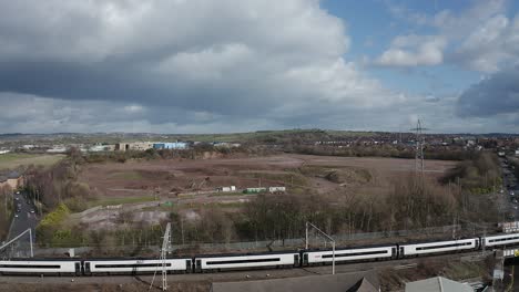 Aerial-footage-of-trains-approaching-Stoke-on-Trent-train-station-in-the-midlands-by-the-canal,-waterside-and-A50-motorway