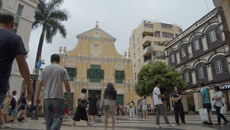 Turistas-Caminando-En-La-Pequeña-Plaza-Cerca-De-La-Calle-De-Estilo-Barroco-De-Color-Amarillo