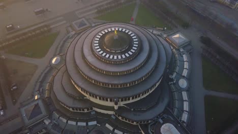 Aerial-shot-of-a-Centennial-Hall-in-Wroclaw,-camera-panning-down-while-approaching-the-top-of-the-roof