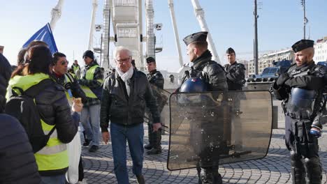 Demonstrant-Mit-Gelber-Jacke-Und-Französischer-Flagge-Spricht-In-Voller-Kampfmontur-Mit-Der-Polizei