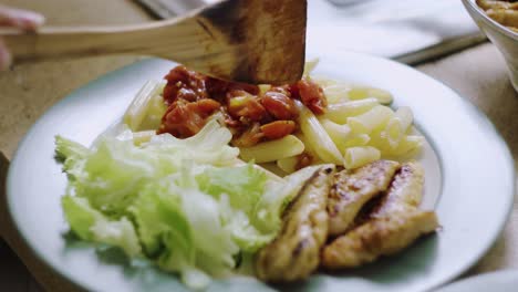 Sirviendo-El-Almuerzo-Con-Pasta,-Filete-De-Pollo,-Ensalada-Y-Salsa-De-Tomate