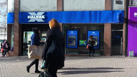 People-using-a-Halifax-ATM,-cash-machine-to-withdraw-money,-deposit-cash-or-pay-some-bills-on-the-high-street-in-the-city-centre