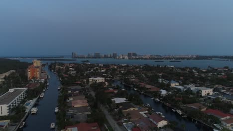 Aerial-shot-flying-near-houses-in-North-Miami-with-buildings-on-the-coast-in-the-background