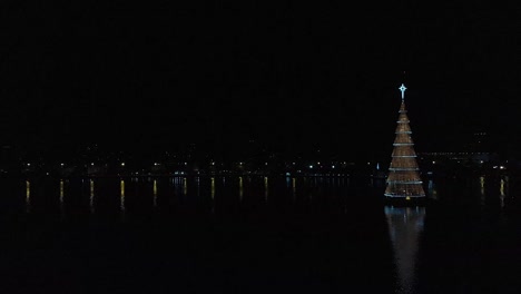 Aerial-approach-and-half-circle-around-of-the-tallest-floating-Christmas-tree-in-the-world-with-changing-lights-in-the-evening-in-the-city-lake-of-Rio-de-Janeiro,-Brazil,-2018