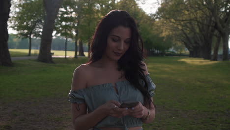 Attractive-young-brunette-latina-woman-in-a-casual-outfit,-uses-her-smartphone,-smiles-happily-to-the-text-messages,-looks-around