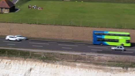 Toma-Aérea-De-Seguimiento-De-La-Carretera-Costera-A259-Cerca-De-Brighton,-Reino-Unido-Con-Los-Infames-Autobuses-Green-Brighton---Hove-Que-Pasan-Por-El-Marco