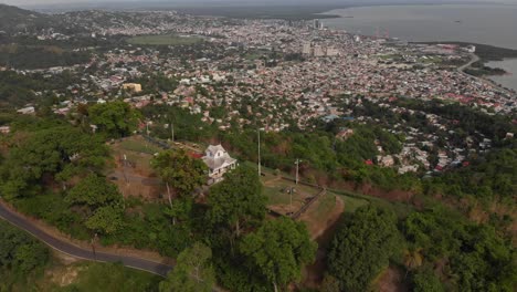 Luftaufnahme-Einer-Festung-Mit-Restaurierten-Kanonen-Und-Der-Stadt-Port-Of-Spain-Im-Hintergrund