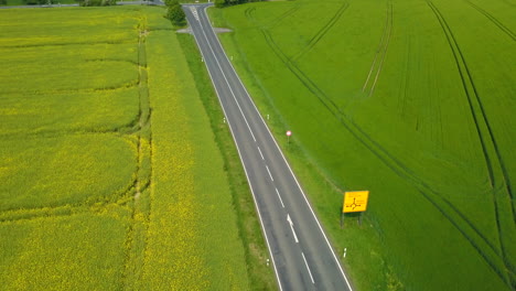 Aerial-view-of-cars-driving-through-an-agriculutural-area-during-summer