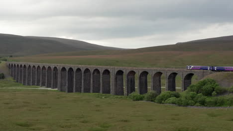 Aerial-Following-Shot-of-a-Northern-Train-Crossing-Ribblehead-Viaduct-in-the-Yorkshire-Dales-National-Park-with-a-Narrow-Crop