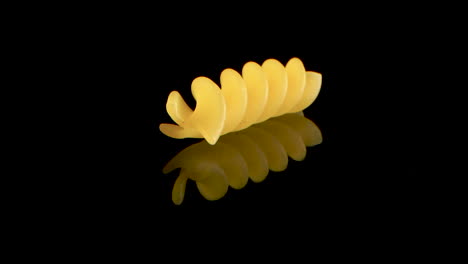 Sliding-over-one-Fusilli-Spiral-Pasta-On-black-mirrored-surface