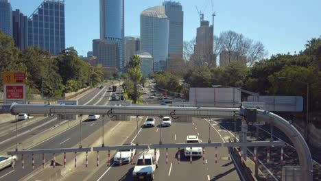 Imágenes-De-Una-Concurrida-Autopista-De-La-Ciudad-De-Sydney-Desde-Un-Puente-Con-Un-Edificio-De-Oficinas-En-Un-Día-Claro-Y-Soleado,-Nsw,-Australia