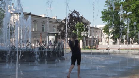 Mädchen-Spielt-In-Zeitlupe-Während-Eines-Heißen-Sommers-Auf-Einem-Brunnen-Auf-Einem-Platz-In-Polen