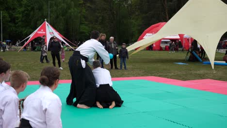 Hombres-Vestidos-Con-Ropa-Tradicional-Y-Mostrando-Movimientos-De-Aikido-A-Sus-Alumnos