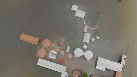 4K-Luftaufnahme-Von-Oben-Nach-Unten,-Rotierend,-Zeigt-Eine-Schule-Auf-Der-Majuli-Flussinsel,-Die-Von-Den-Überschwemmungen-Des-Brahmaputra-Monsuns-überschwemmt-Ist