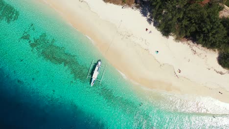 Top-View-White-Sand-Beach-With-Fishing-Boat-Floating-By-the-Sea-With-and-Glorious-Trees---Aerial-Shot