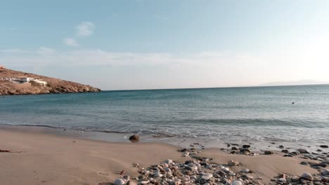 The-beachside-view-of-Ormos-Giannaki-Beach-on-the-island-of-Tinos-with-many-rocks-in-the-sand