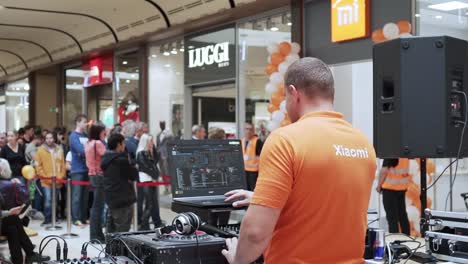 Xiaomi-DJ-plays-some-music-for-people-waiting-in-line-in-front-of-a-shop,-static-slowmo-shot