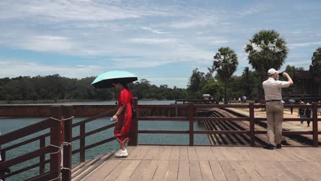 Tourists-Walking-Down-Stairs-on-Bridge-While-Man-Finishes-Taking-Photos-at-Angkor-Wat