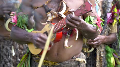 Man-plays-ukulele-while-wearing-traditional-dress-and-pig-tusk-necklace