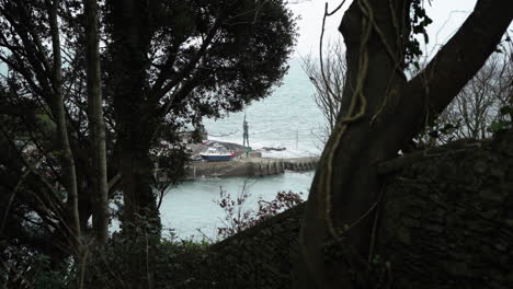 Distant-View-Through-The-Trees-Of-Verity-Statue-Standing-At-The-Harbour-Of-Ilfracombe,-United-Kingdom---high-angle-shot