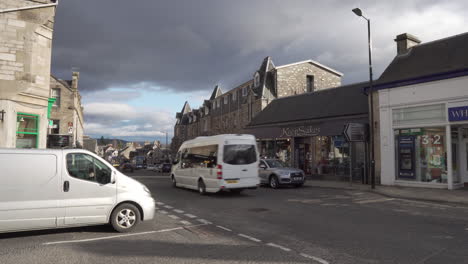 Static-shot-from-Pitlochry-city-in-Scotland-during-a-busy-day-in-the-city-center-with-people-and-cars-passing-by-with-wonderful-morning-sunlight