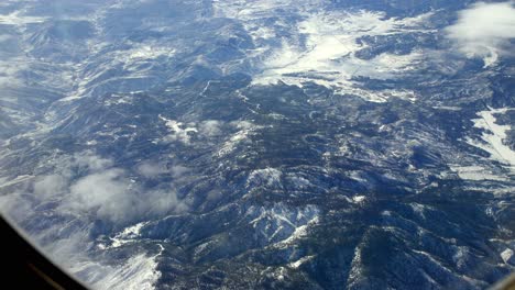 Snowed-Mountains-over-northern-California-during-winter,-Aerial-airplane-window-shot