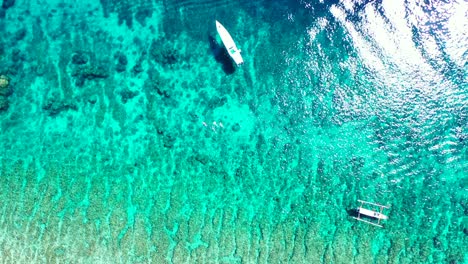 Eine-Atemberaubende-Landschaft-Auf-Den-Philippinen-Mit-Booten,-Die-An-Einem-Sonnigen-Tag-Auf-Dem-Grünen-Meer-Schwimmen---Luftaufnahme