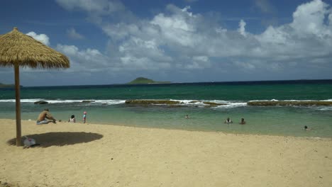 A-white-sandy-beach-for-relaxing-on-the-Caribbean-island-of-Grenada-with-persons-playing-in-the-sand