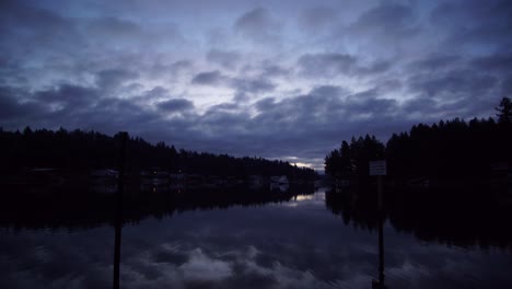 Blue-hour-time-lapse-of-sunrise-over-Wollochet-Bay-near-Gig-Harbor,-Washington,-streaming-clouds,-purple-to-bright-white-sky,-reflection-on-the-water