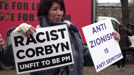 UK-November-2019:-Protestors-hold-up-placards-calling-Labour-leader-Jeremy-Corbyn-a-racist,-terrorist-supporter-and-stating-anti-Zionism-is-anti-Semitism