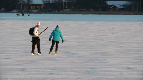 Couple-enjoying-ice-skating-on-natural-ice,-winter-activities-on-a-lake-in-Ostrobothnia,-Finland