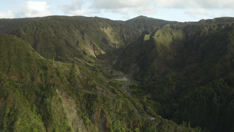 Two-cars-make-their-way-through-the-winding-roads-of-the-Azores,-aerial-establishing-shot