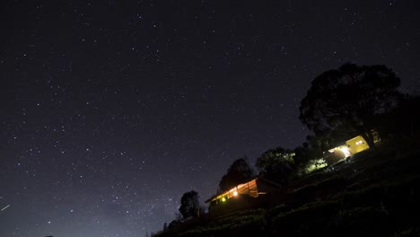 Time-lapse-De-Estrellas-En-Movimiento-En-El-Cielo-Nocturno-Cerca-De-Un-Par-De-Pequeñas-Cabañas-Filmadas-En-4k